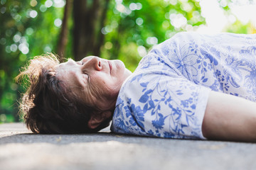 Old woman is lying on the ground happy – Elder on the street smiling with her eyes closed