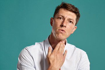 Portrait of a young brunet man posing in a studio against a blue background.