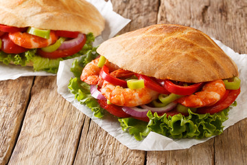 Pita with king prawns, summer vegetables close-up on paper. horizontal
