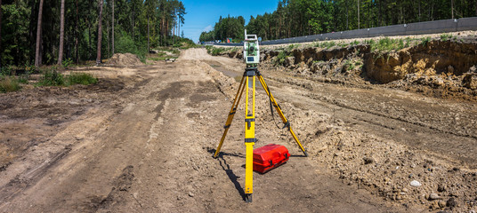Panoramic view of surveyor equipment (theodolite or total positioning station) on the construction site of the motorway or road - obrazy, fototapety, plakaty