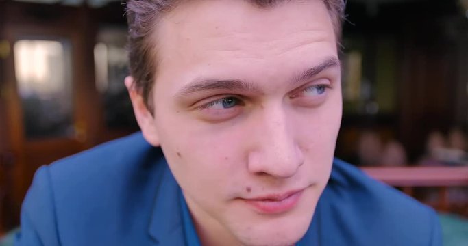 A young confident businessman looks into the camera and winks, agrees, despises. Blue eyes, Caucasian, freelancer, luxury apartments, portrait, close-up