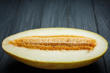 Fresh half of melon with seeds. On dark wooden background. Top view.