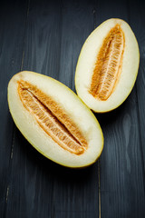 Fresh half of melon with seeds. On dark wooden background. Top view.