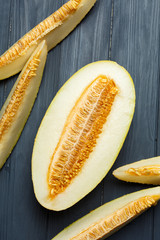 Fresh half of melon with seeds. On dark wooden background. Top view.
