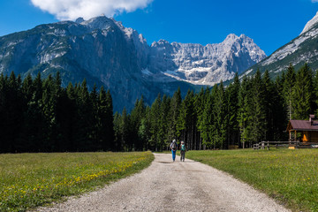 Fototapeta na wymiar Landscape in dolomites, Unesco world heritage. Two people walking on a road among the mountains