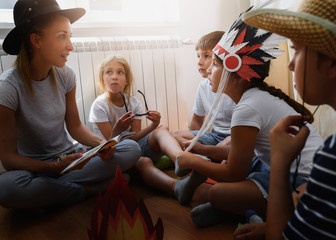 Preschool teacher reading a story to children at kindergarten. Mother reading to the children.