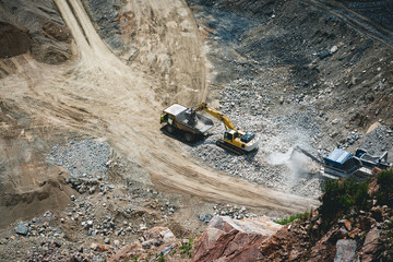 Excavator loading dumper truck on mining site stock photo