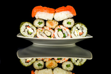 Sushi spread out on a plate on a black background