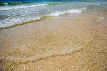 Soft blue ocean wave on sandy beach. Bottom. White sand on the beach with turquoise water in Djerba, Tunisia.