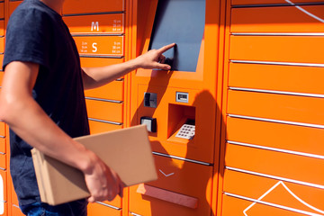 Man client using automated self service post terminal machine or locker to deposit the parcel for storage