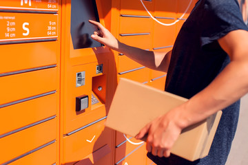Man client using automated self service post terminal machine or locker to deposit the parcel for...