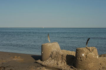 A small castle of sand, with the ocean as backdrop