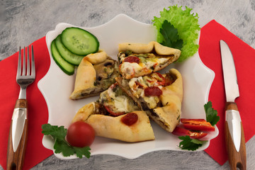Fast food - mini pizza with cheese and mushrooms. Slices of fresh vegetables with parsley and salad leaves. Traditional Italian recipe for dinner.