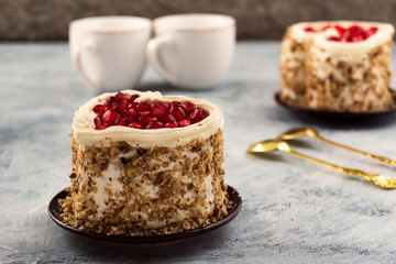 Festive heart-shaped cake decorated with pomegranate seeds and chopped nuts.