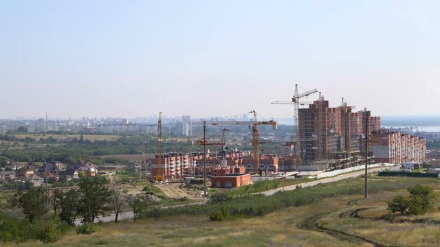 Several tower cranes build a multi-storey building and move cargo, long-range plan, time-lapse