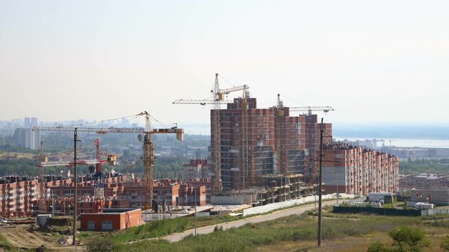 Several tower cranes build a multi-storey building and move cargo, long-range plan, time-lapse