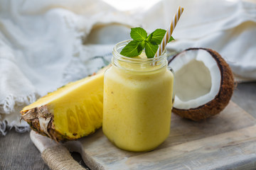 Photo of pineapple smoothie in jar with straw on light background. Fresh organic Smoothie. Health or detox diet food concept.