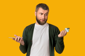 Emotional man doubtfully looking at credit card