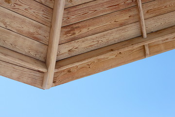 Close-up of a part of a wooden beach umbrella against a blue sky