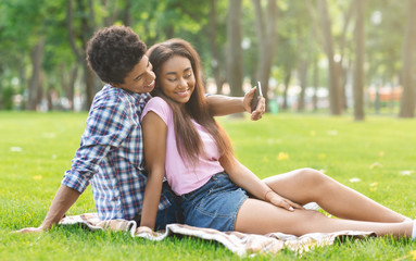 Romantic teenagers taking selfie on a date in park