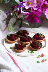 Shortbread tartlets with berry custard and flowers on a light background.