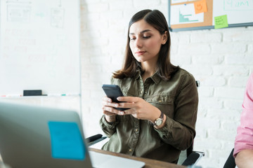 Businesswoman Texting On Mobile Phone In Office