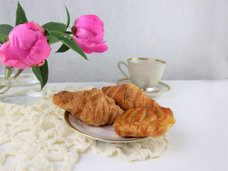 breakfast with cup of coffee and croissants, bouquet of pink flowers