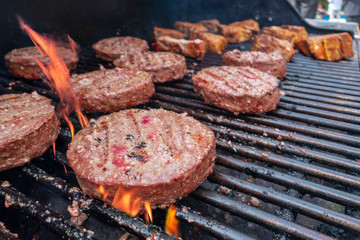 close up of hamburgers and lamb chops on a gass outdoor grill