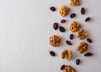 A variety of peeled walnuts and raisins on a white wooden background. View from above. Plenty of space for text.