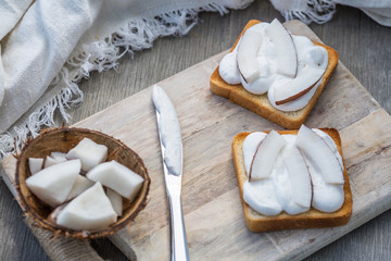 Toast with coconut on wipped cream on a wood board on light background. Summer traditional homemade dessert.