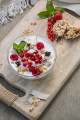 Bowl of fresh mixed berries and yogurt. Photo of breakfast bowl with farm fresh strawberries red currant and blackberries served on a wooden board.