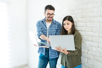 Professionals With Laptops Against Wall In Office