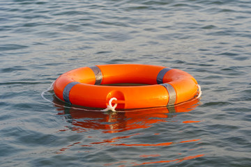 Orange lifebuoy in sea on water. Life ring floating on top of water. Life ring in ocean.