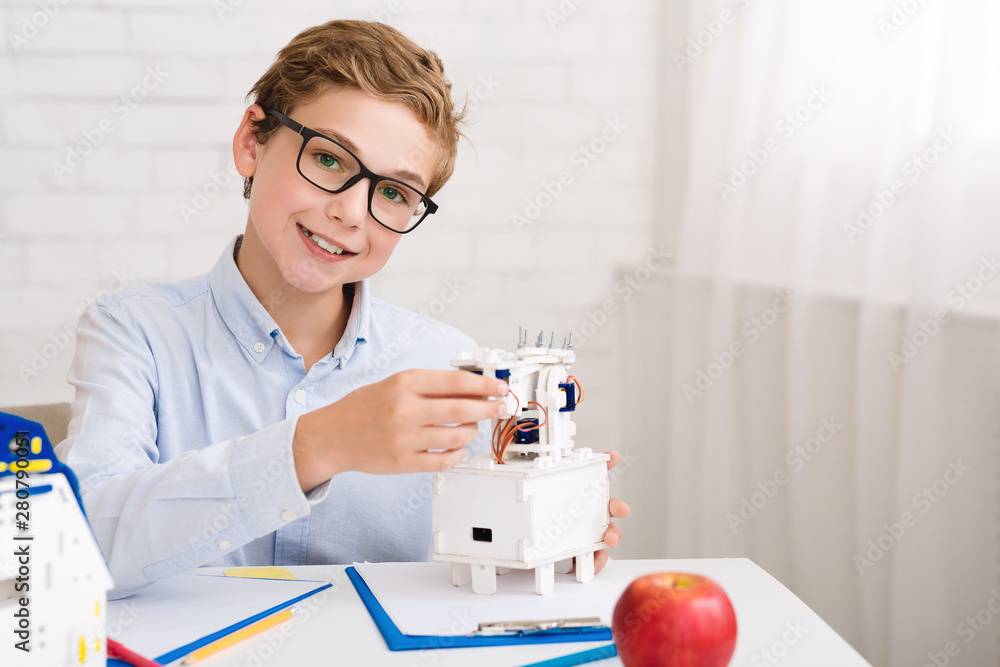 Poster Happy boy constructing electric robot and looking at camera