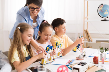Teacher helping her students with diy robots