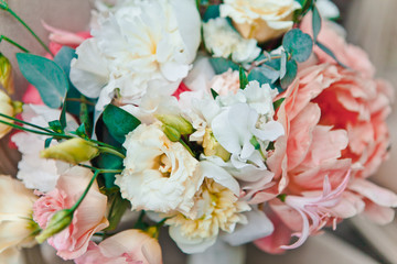 Close-up bridal bouquet of fresh spring and summer flowers in pastel colors stand on a classic chair, selective focus