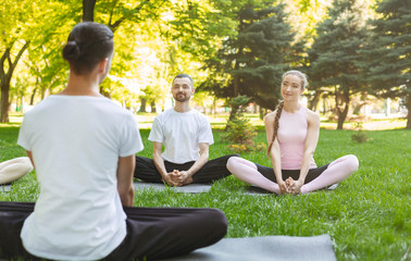 Yoga beginners listening to instructor sitting in Lotus pose