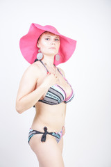 cute stylish bright plus size woman in striped swimsuit with big fuchsia beach hat on white isolated studio background alone