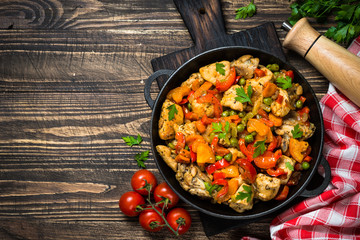 Chicken Stir fry with vegetables on wooden table.