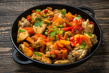 Chicken Stir fry with vegetables on wooden table.