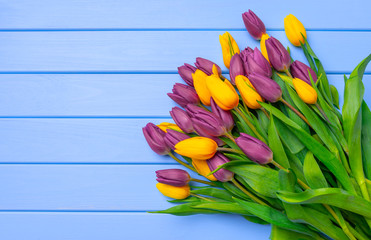 A bouquet of tulips on a table of blue wooden boards.