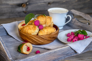 Croissants with raspberries on a wooden tray. The concept of a wholesome breakfast.