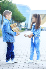 Naklejka premium Little students hold a lot of books. The concept is back to school, education, reading, friendship and family.