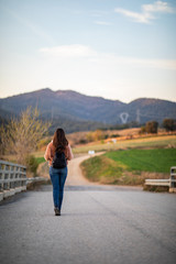 Beautiful woman hiking over a bridge with the path and mountains blurred on the background