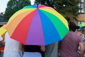 People standing under an umbrella with pride colors 