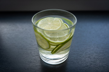 A glass of a refreshing drink, a cocktail with sliced ​​lime on a grey background. 
