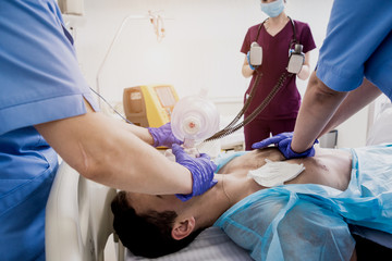 Doctors give resuscitation to a male patient in the emergency room. Cardiac massage - obrazy, fototapety, plakaty