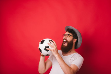 Photo of cheerful amazed man catching soccer ball over red background