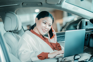 Smiling woman talking on her phone in a parked car.