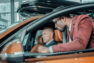 Serious man sitting in a car in salon.